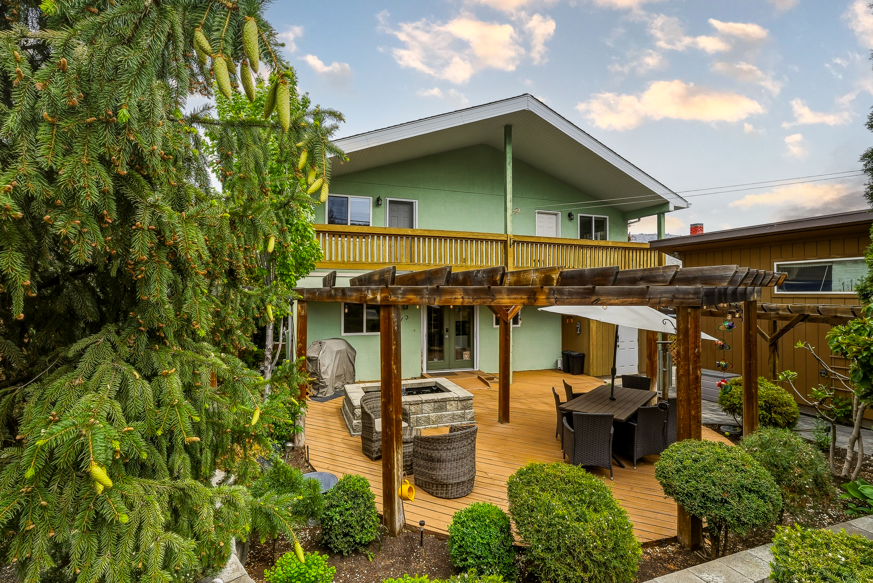 Back deck at 1127 Columbia St with full pergola overhead, outdoor dining set, stone water feature and mature greenery