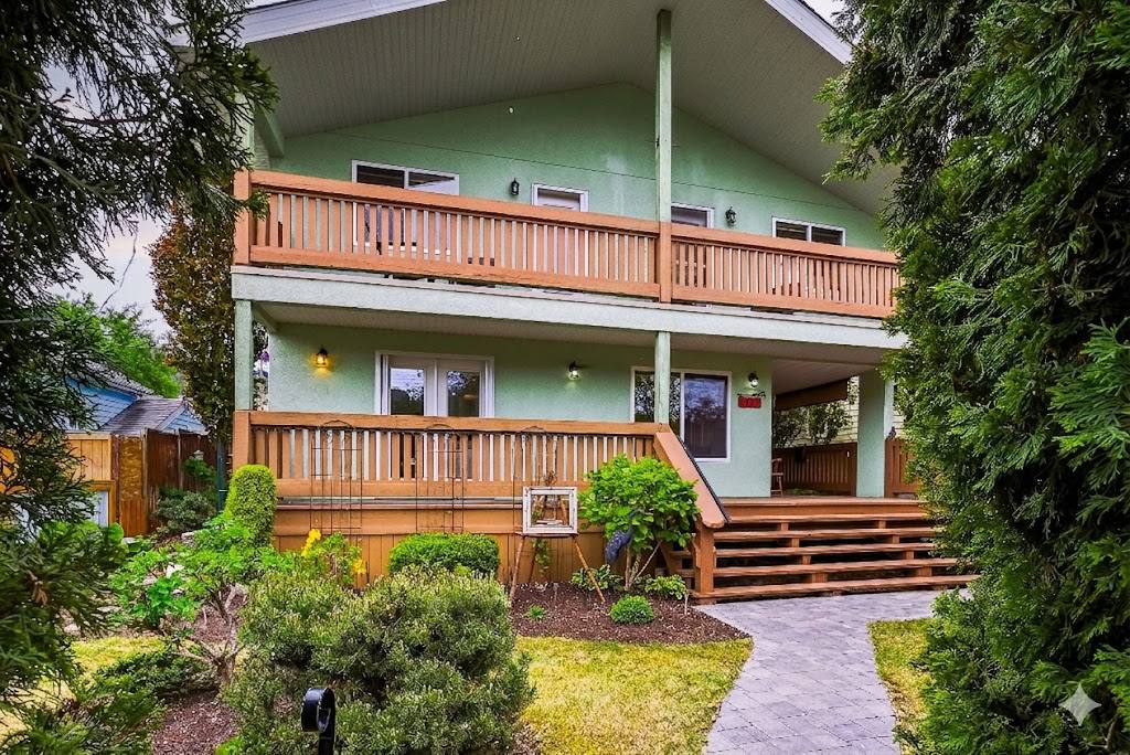 Front of 1127 Columbia St with sage-green siding, covered upper and lower verandas, paver walkway and mature landscaping