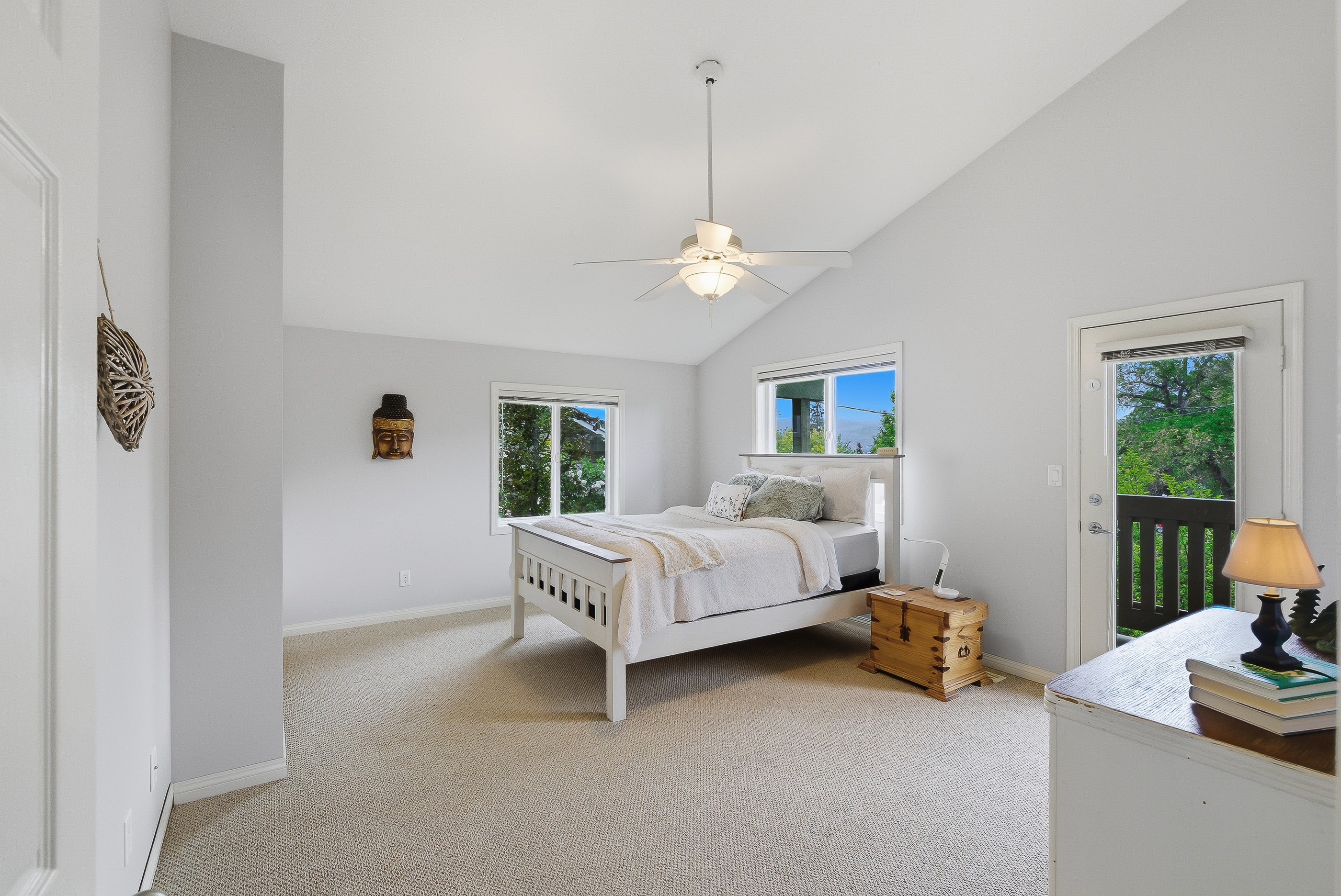 Upstairs primary bedroom with vaulted ceiling, queen bed, walk-out door to a private upper balcony