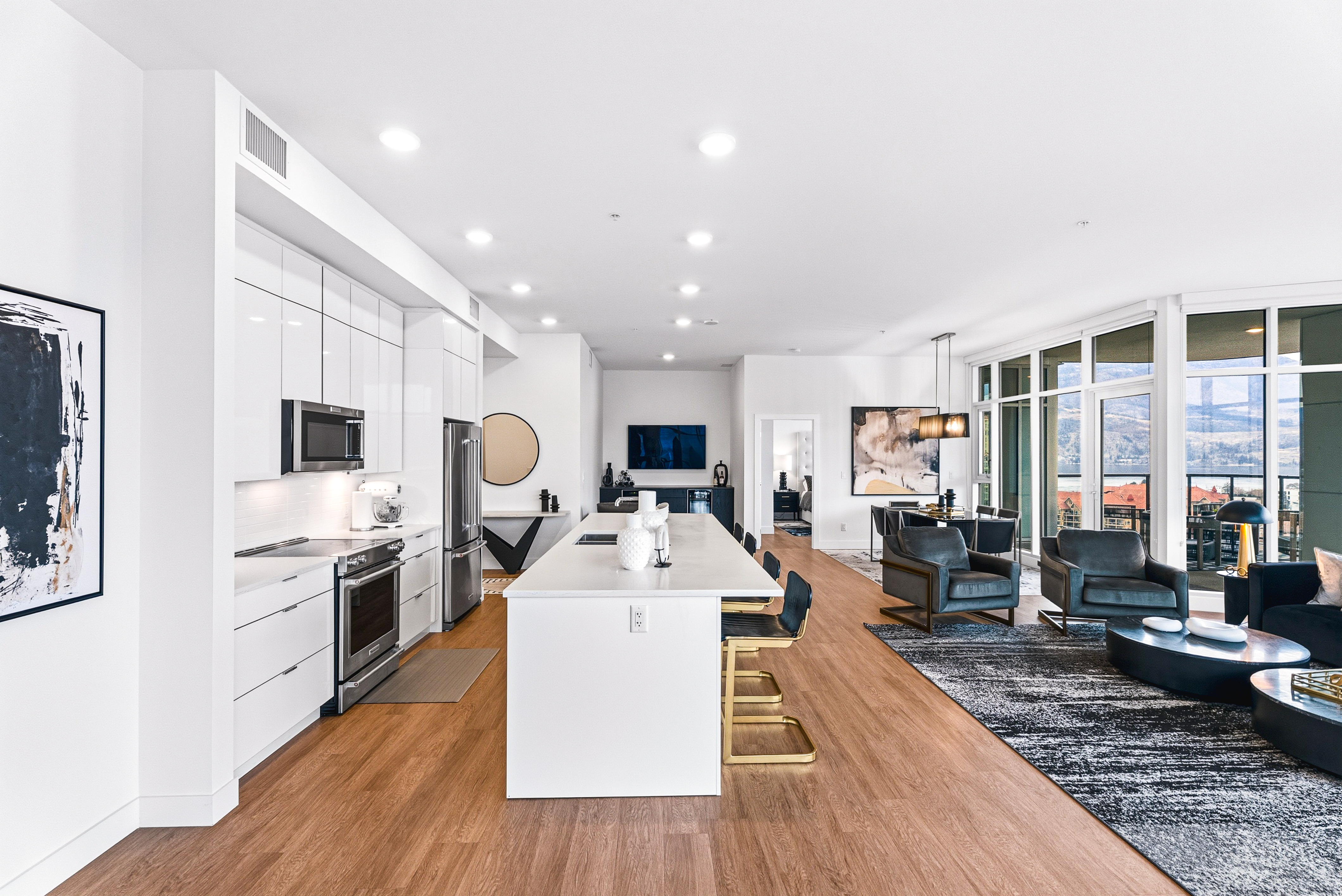 Kitchen and living area with curved floor-to-ceiling windows looking out at the lake and mountains