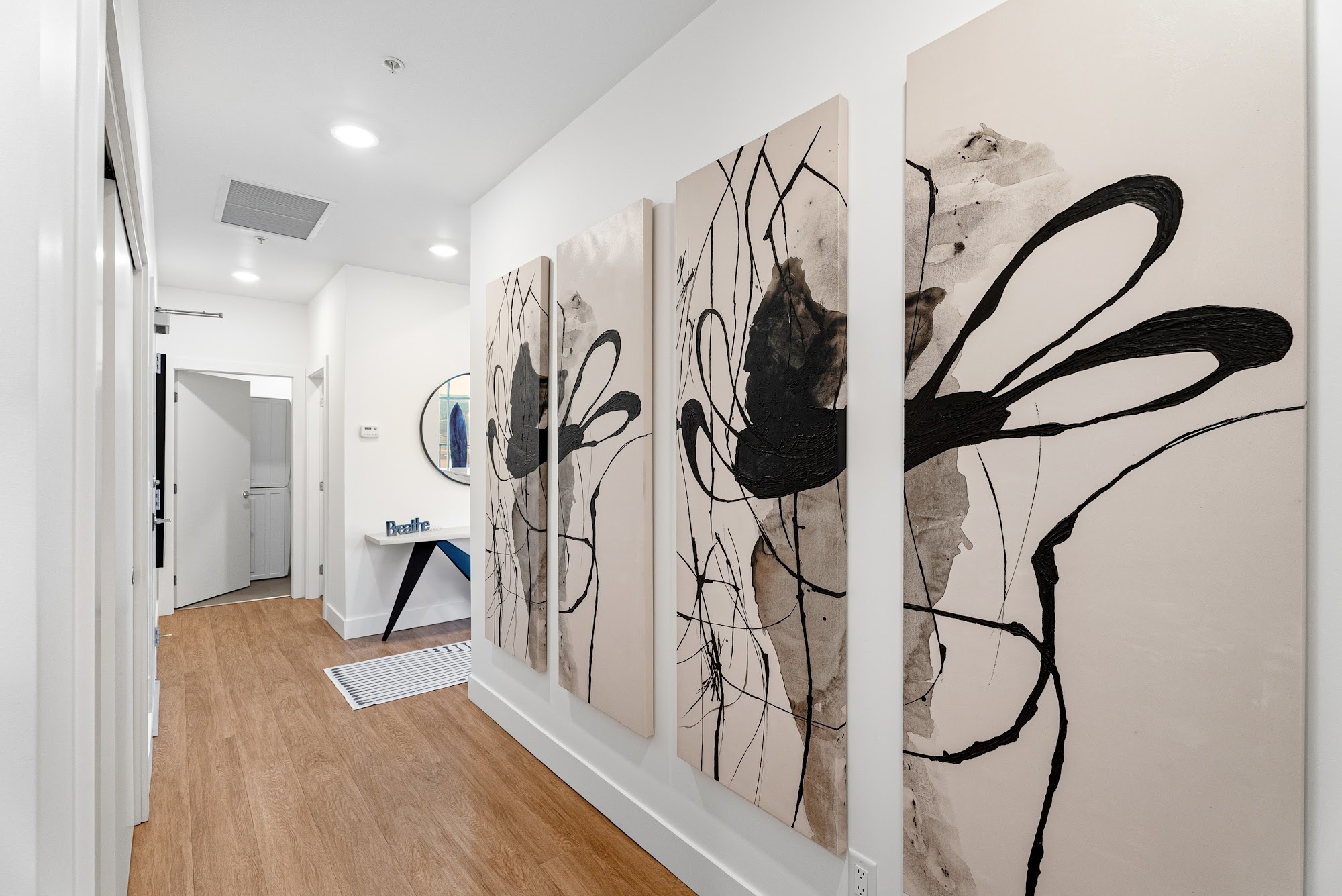 Entry foyer with sculptural pendant and gallery wall leading into the open plan