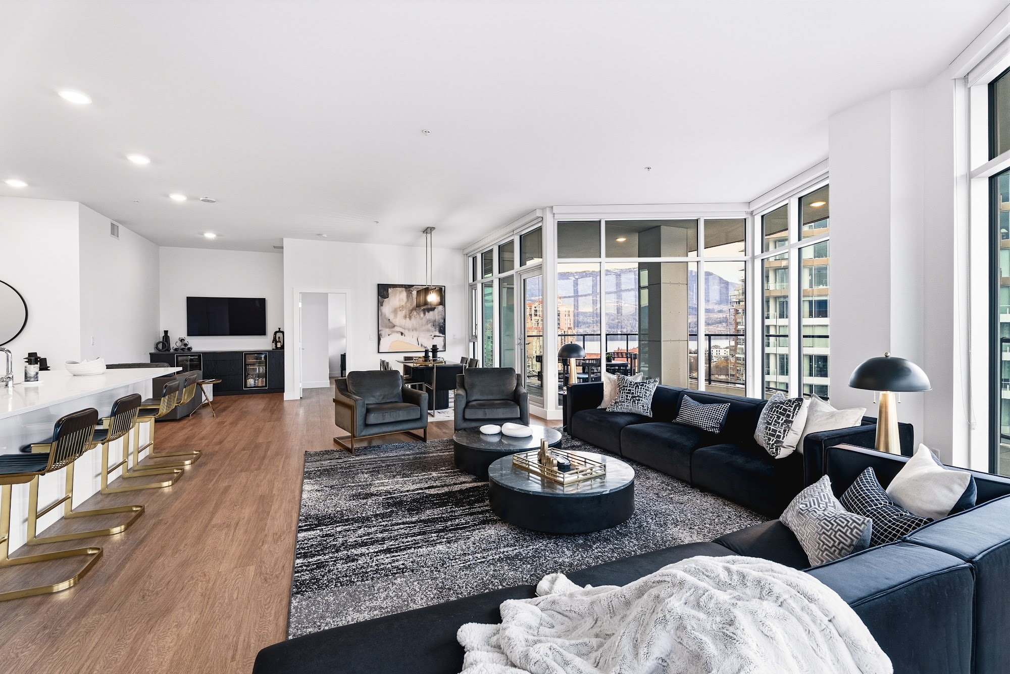 Living room with deep navy sectional, wood floors, gallery art and the deck doors off the side